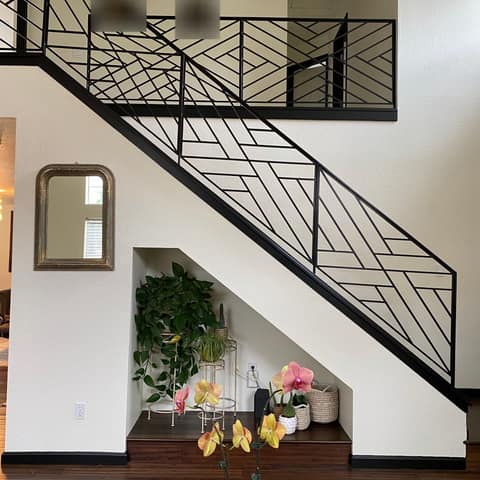 After: the same stair with a new black steel railing in a geometric diagonal bar pattern.