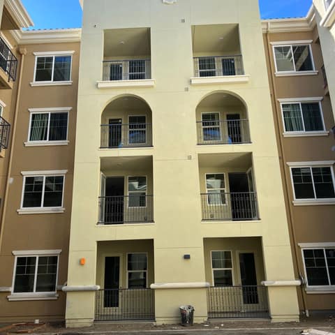 Four-story apartment building with black ornamental iron balcony railings with scroll details at every unit.