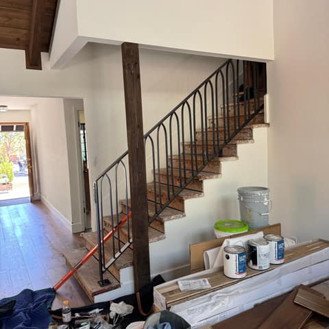 Black steel stair railing with arched pickets on an interior staircase during a home remodel.