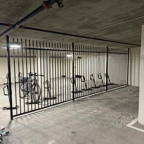 Black painted picket security fence enclosing a bike storage area in a concrete parking garage