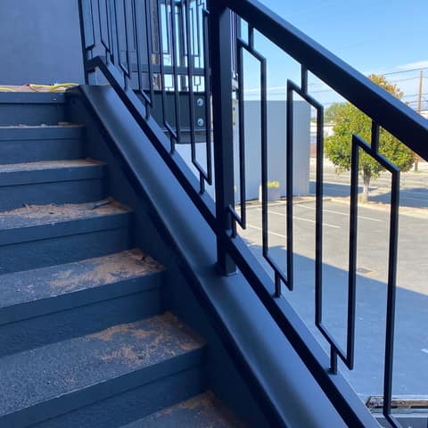 Black steel exterior stair railing with a geometric rectangle picket pattern on a commercial building.
