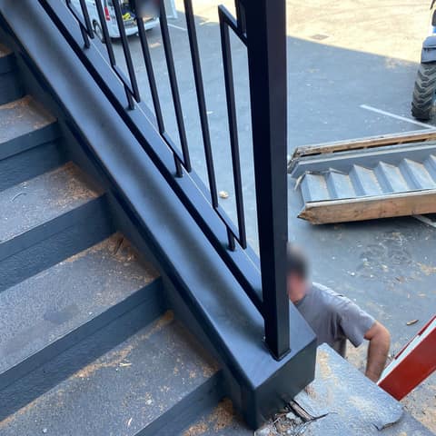 Same black geometric stair railing, seen from above at the bottom post.