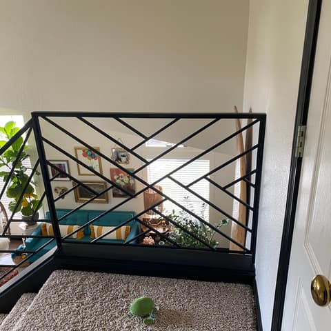 Black steel guardrail with an angled geometric bar pattern at an upstairs landing.