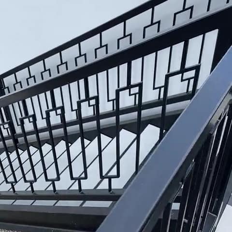 Short video: looking down along a black geometric steel stair railing on a commercial building.