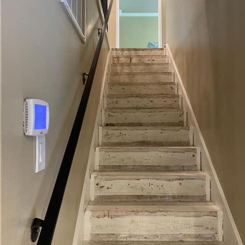 Black steel wall-mounted handrail running up a narrow interior staircase.