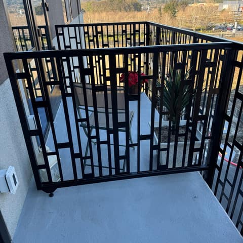 Black laser-cut steel balcony railing with a geometric rectangle pattern on an upper-floor apartment.