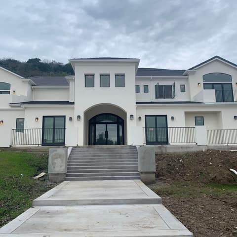 New two-story home with black steel guardrails and balcony railings across the front terraces.