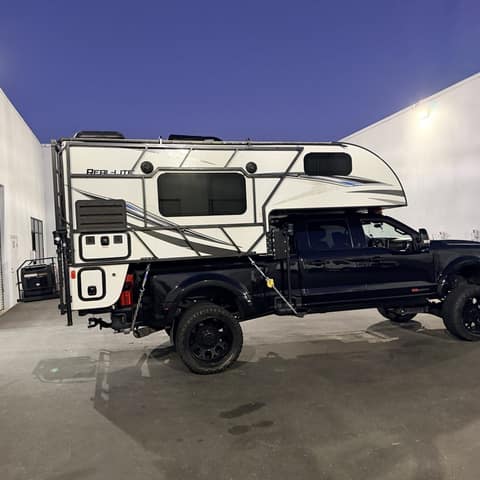 Black steel tube rack frame wrapped around a truck camper on a lifted pickup