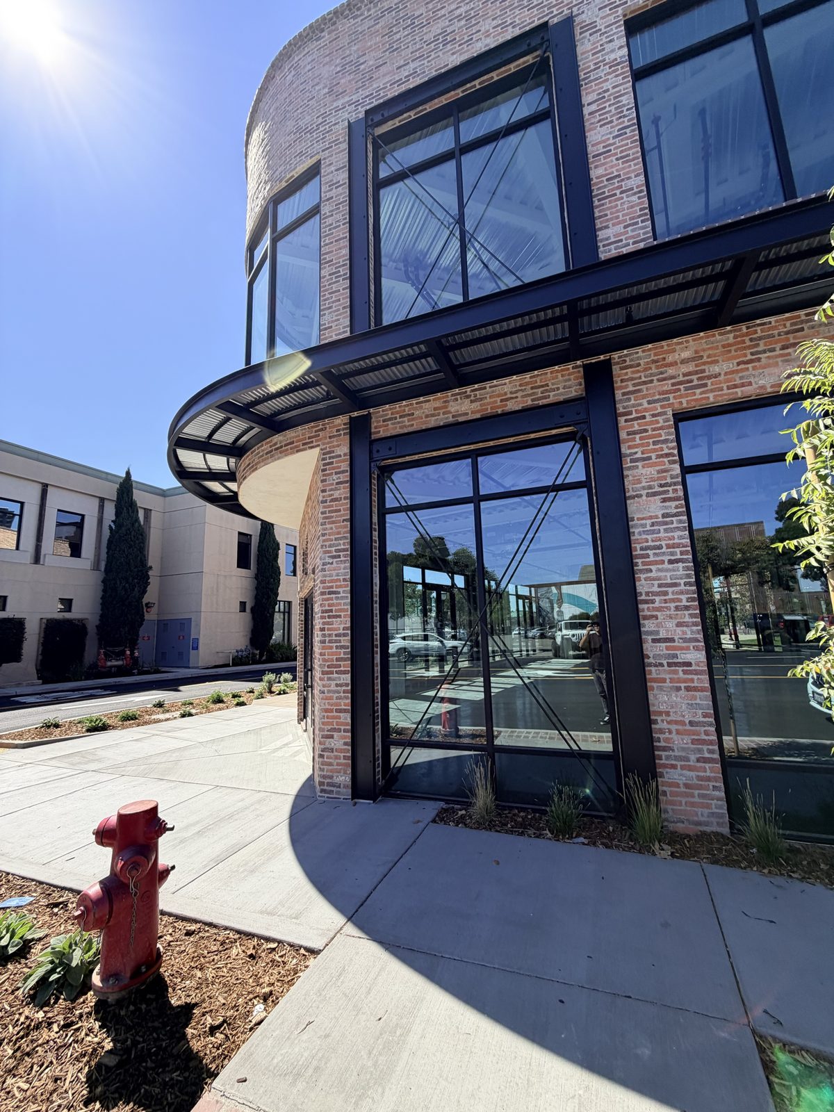 Curved black steel awning with corrugated metal deck wrapping the corner of a brick building