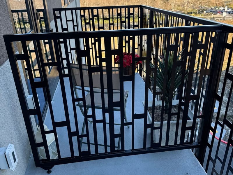 Black laser-cut steel balcony railing with a geometric rectangle pattern on an upper-floor apartment.