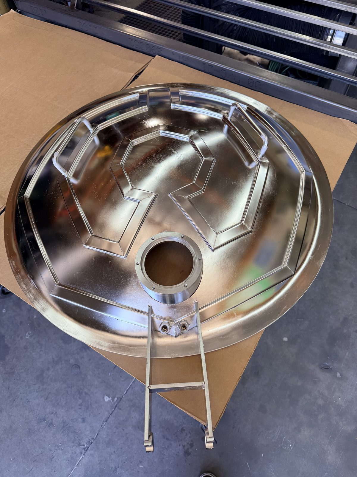 Mirror-polished stainless steel dish with welded handles and a machined port